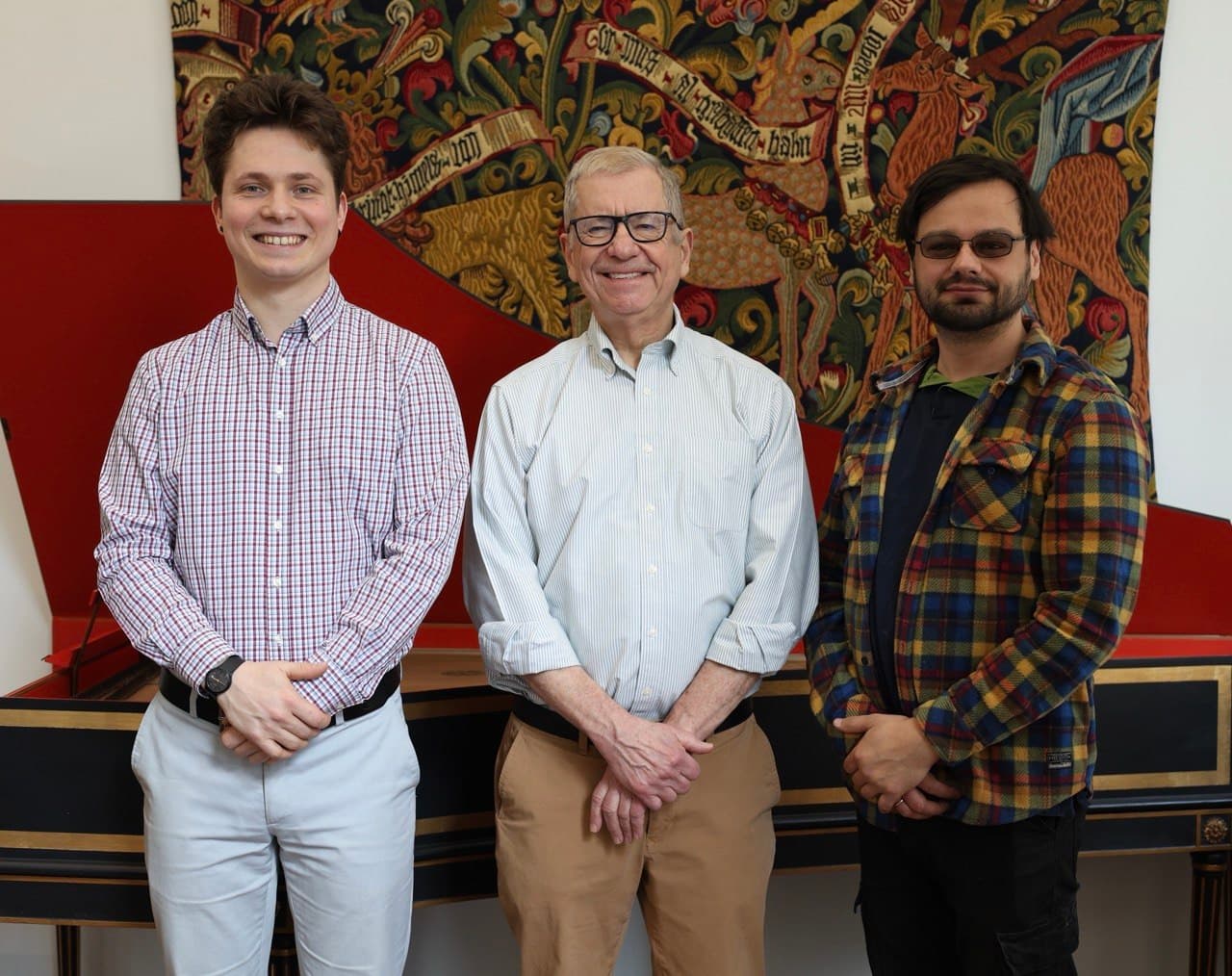 The team of the Lviv Early Music Foundation in front of a French harpsichord and Renaissance tapestry